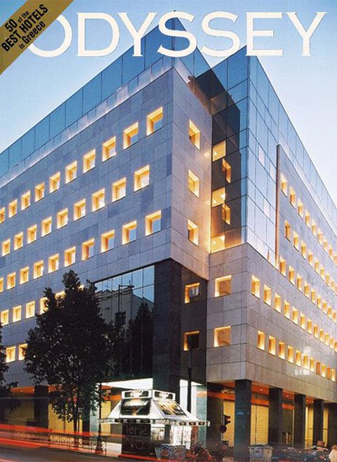 A modern multi-story building at dusk with illuminated windows, featuring a magazine header "odyssey" at the top.