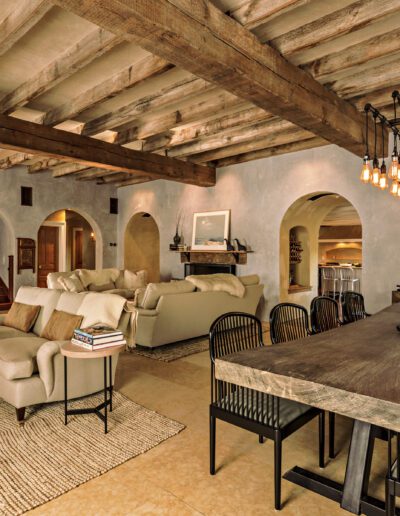 Rustic elegant interior with exposed wooden beams, a long dining table, and a cozy living area.