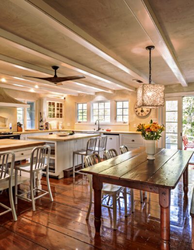 Spacious rustic kitchen with a large wooden dining table, kitchen island, and a fireplace.