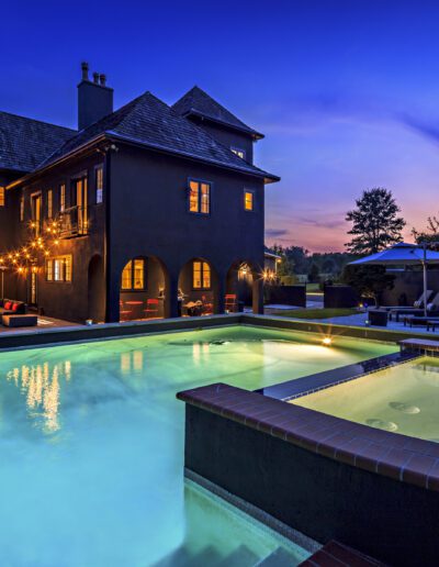 Luxury home with pool and spa illuminated at twilight.